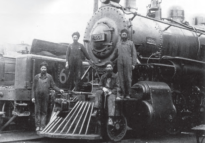 Black and white photo of Sikh railway workers standing on a steam train locomotive in the early 1990s in British Columbia 